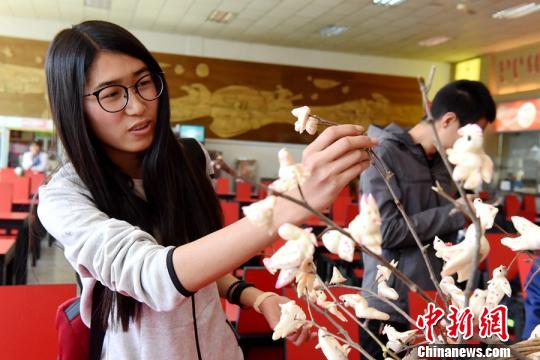 图为大学生将捏好的面食“寒燕”挂起来。　曹艺 摄